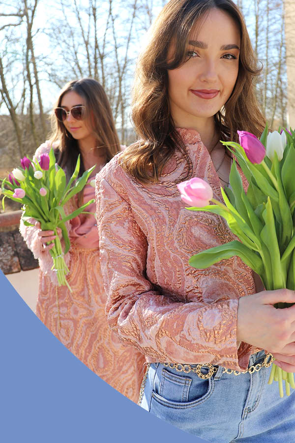 Zwei Frauen mit Tulpensträußen in der Hand und modisch gemusterten Outfits.