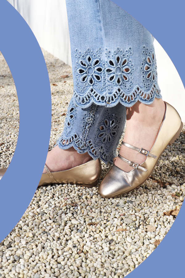 Frau mit goldschimmernden Ballerinas und trendiger Jeanshose mit floralem Lochmuster
